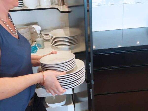 Removing plates from the kitchen cupboard to clean the cupboard